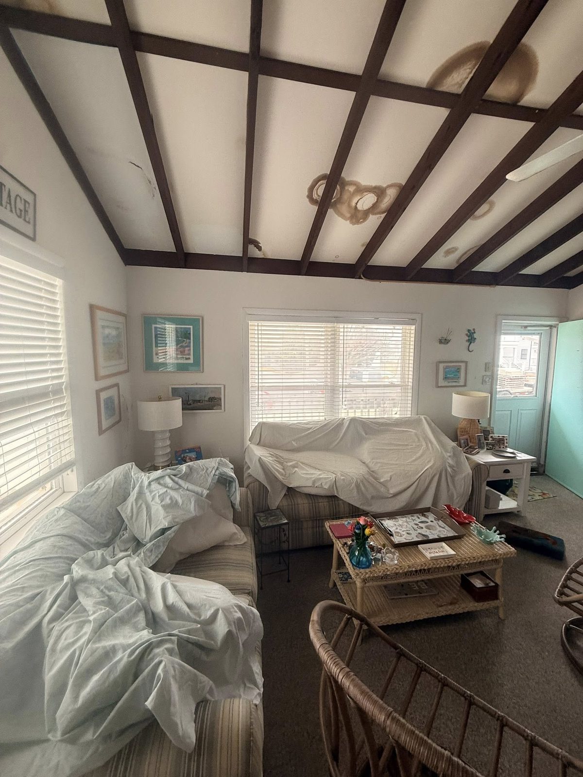 Before: living room with furniture covered, ceiling stained